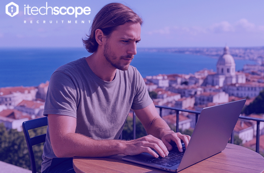 Man on computer doing work out side with a backdrop of a city landscape behind him.