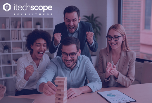 Four cheerful office colleagues gathered around a table, excitedly playing a game of Jenga. One person is pulling a block while the others cheer and clap, creating a lively and collaborative atmosphere.
